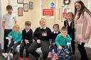 Harlan, Freya, Rory, Zac, Abigail, Caleb, Emilia and Mrs Hamilton testing the buddy bench donated by the Thistles to Alva PS