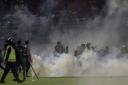 Police officers and soldiers stand amid tear gas smoke during a soccer match at Kanjuruhan Stadium in Malang, East Java, Indonesia