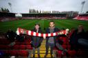 Rob McElhenney and Ryan Reynolds hold opposing ends of a Wrexham scarf