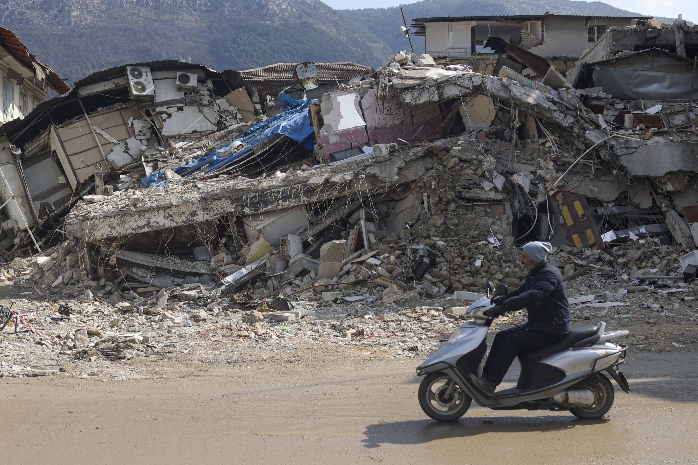 A man rides a motorbike past destroyed buildings in Antakya, southeastern Turkey, Tuesday, Feb. 21, 2023. The death toll in Turkey and Syria rose to eight in a new and powerful earthquake that struck two weeks after a devastating temblor killed nearly